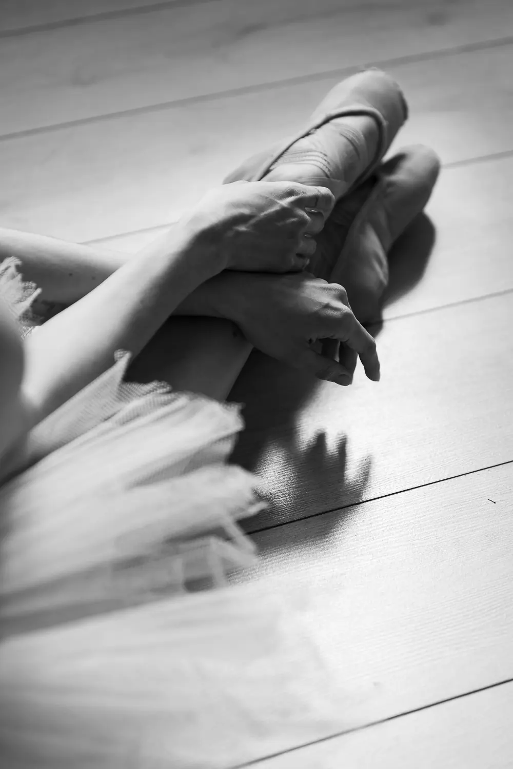 Zapatillas de punta y tutú de una bailarina sobre el piso del escenario, en blanco y negro